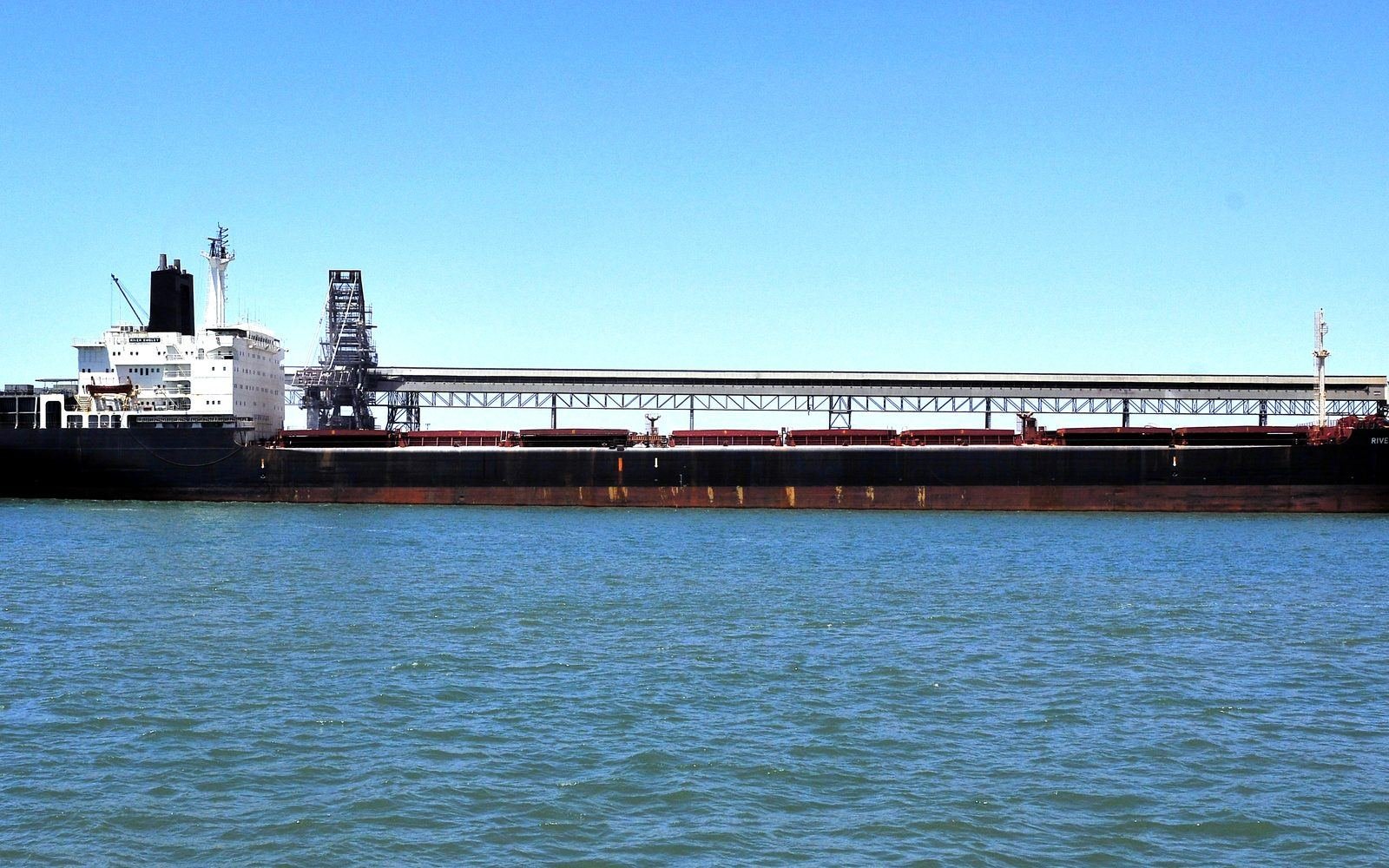 A bulk carrier alongside a coal terminal, loading arms in view